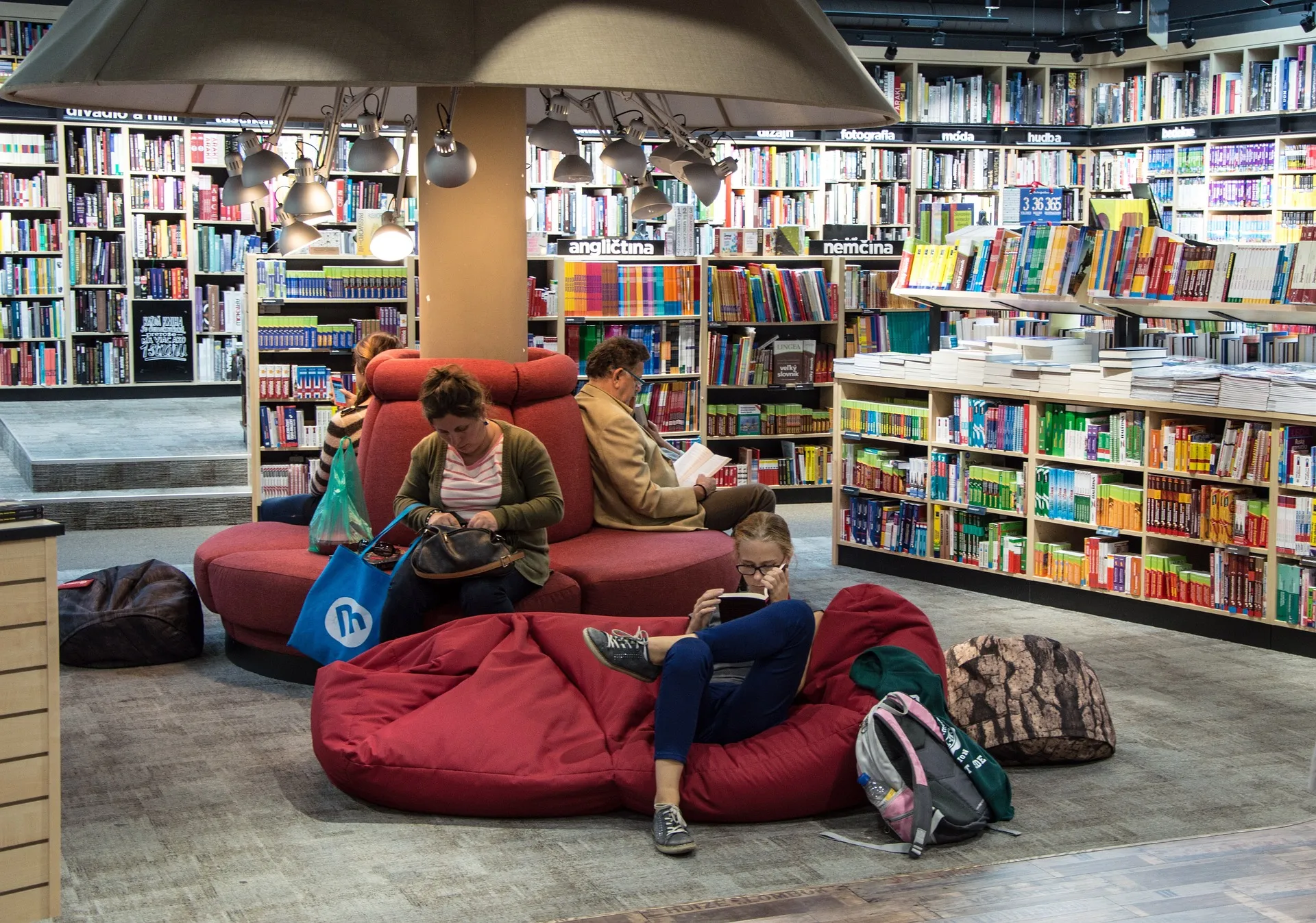People sitting and reading books among bookshelves.
